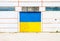 Wall of ancient warehouse with door in ukrainian flag colors - blue and yellow. Ukrainian flag on background of old locked doors