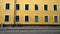 Wall bright yellow house with lots of beautiful Windows. To the wall leaning the bike. Near a small post