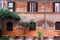 wall of a building with potted plants. Charming facade with shutters. Paved sidewalk