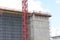 Wall of a building under construction with a multi-storey crate and a construction crane mast, Moscow, June 2021