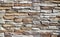 Wall cladding for exterior made of irregular and embossed natural stones with different sizes. Colors are white and light brown.