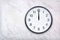 Wall clock show the twelve o`clock on white marble texture. Office clock show midday or midnight