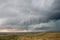 A wall cloud gathers under the base of a supercell storm in the prairie.