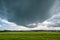 Wall cloud of a supercell thunderstorm over green fields