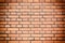 A wall with even rows of orange bricks. Accurate brickwork. Empty textural background. Photo with a vignette.