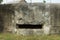 The wall of a gray old concrete historical bunker with an embrasure