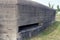 The wall of a gray old concrete historical bunker with an embrasure