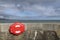 Wall with a lifebuoy case in the corner with the sea and clouded sky