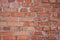 The wall is lined with red brick with small cracks, resmeared with mortar, background