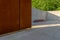 Wall made of architectural concrete and corten sheet surrounded by greenery in the park, a bicycle rack standing on a concrete