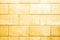 The wall is made of stone blocks of yellowed color with scuffs and damage. Yellow background with brick texture