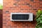 Wall mounted air conditioner is pictured on brick wall. This versatile image can be used to showcase cooling systems, en