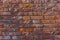 A wall of old, cracked bricks, with a weathered and faded surface.