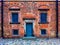 wall of the old red brick with dark door and symmetrical windows