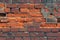 Wall of old red clay bricks. Ruined vintage stone background. Rough aged masonry backdrop. Surface of grunge brick