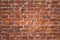 Wall of old red clay bricks. Ruined vintage stone background. Rough aged masonry backdrop. Surface of grunge brick