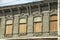 The wall of an old wooden building with boarded up windows. Magnificent wood carvings on window frames and cornice