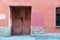 Wall with an old wooden door and a window with iron bars