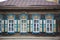 The wall of an old wooden house with carved shuttered windows.