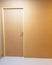 Wall painted brown with wooden door also brown on one side. Frontal view of the whole