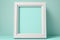 Wall poster realistic mockup. Vertical white picture frame standing on the floor near wall in light cyan studio room.
