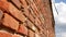 Wall of red old bricks. Blue sky with white clouds