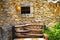 Wall of a rural autumn house with a small window, a wooden bench. Village house in leaf fall