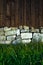 Wall of stones and wooden fence, rockery garden, stones on lawn, dark fence