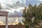 Walled garden patio with evergreens and boxwood overlooking skyline cloudscape