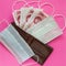 Wallet, disposable protective masks and cash chinese money on pink background. Medicines deficiency, protection in the