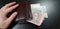 Wallet full with hryvnia banknotes with male fingers on it lay on black table