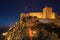 Walls and tower of Castle over rocky cliff at dusk in Marvao