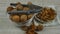 Walnut kernels on white glass saucer, unpeeled walnuts in transparent glass bowl and metal nutcracker. Closeup panorama