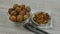 Walnut kernels on white glass saucer, unpeeled walnuts in transparent glass bowl and metal nutcracker. Closeup panorama