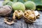 Walnut kernels and whole walnuts lie next to nuts in green shells and green leaves on a rustic old wooden table