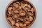 Walnut shell in a round wooden cup on a light background.