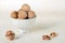 Walnut in a shell are stacked in a white cup. Next peeled nuts. Vegetable protein is an analogue of animal. Light background