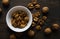 Walnut in a smale plate with scattered shelled nuts and whole nut which standing on a wooden vintage table. Walnuts is a