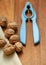 Walnuts with blue nutcracker on wooden board