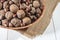 Walnuts and hazelnuts in a bowl. Bowl on burlap. White wooden table.