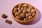 Walnuts heap food in wooden bowl on pink background near to peeled nuts