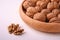 Walnuts heap food in wooden bowl on white background near to peeled nuts