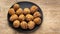 Walnuts in shells are falling onto a black ceramic plate