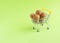 Walnuts in a small miniature cart on a green background. Shopping, shopping center, business concept