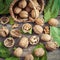 Walnuts and small wicker basket on old wooden table.