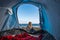 Wanderlust and alternative vacation lifestyle for blonde pretty girl sitting outside of a tent camped on the sand at the beach in