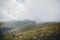 wanderlust and travel concept. girl traveler in hat with backpack walking in clouds in mountains. stylish hipster woman exploring