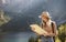 Wanderlust and travel concept. Stylish traveler girl in hat looking at map, exploring woods