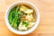 Wanton soup with morning glory and deep fried garlic in bio paper bowl on wooden background