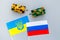 War, confrontation concept. Russia, Ukraine. Tanks toy near russian and Ukrainianflag on grey background top view